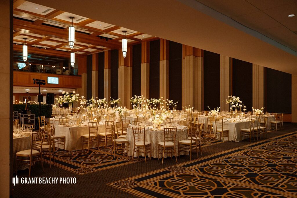 A side view of Danke Ballroom at Notre Dame University. Showing the dept of the candle lit ball room and height of the large white and green floral arrangements through out the ballroom.